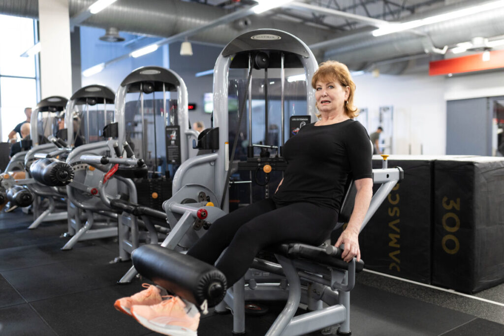 A mature person using a leg extension machine in a gym, focusing on strength training for healthy aging.