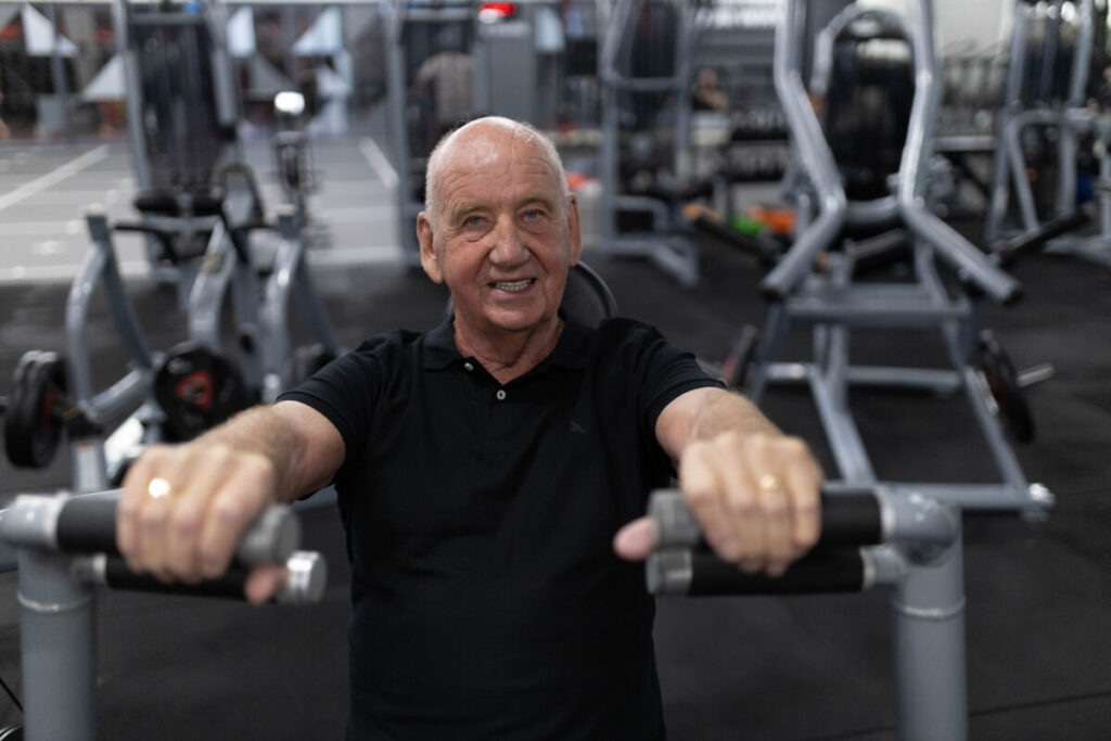 A mature person using a chest press machine in a gym, enhancing upper body strength with weight training