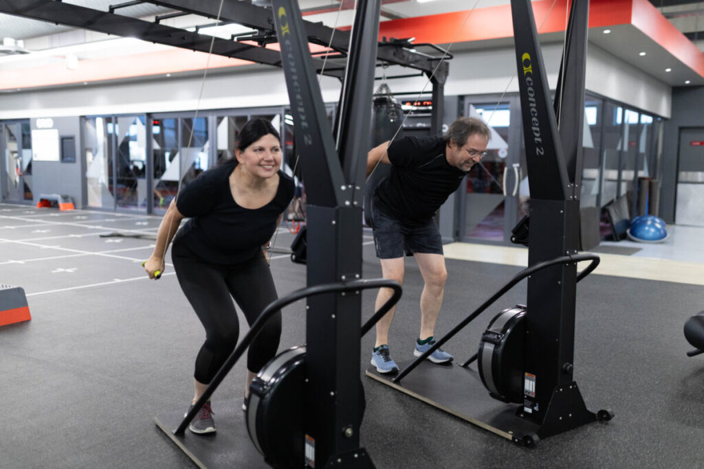 Marcia Swanepoel guiding a client on a ski ergometer at Virgin Active The Sanctuary in Somerset West, promoting cardiovascular fitness and heart health through an engaging cardio workout.