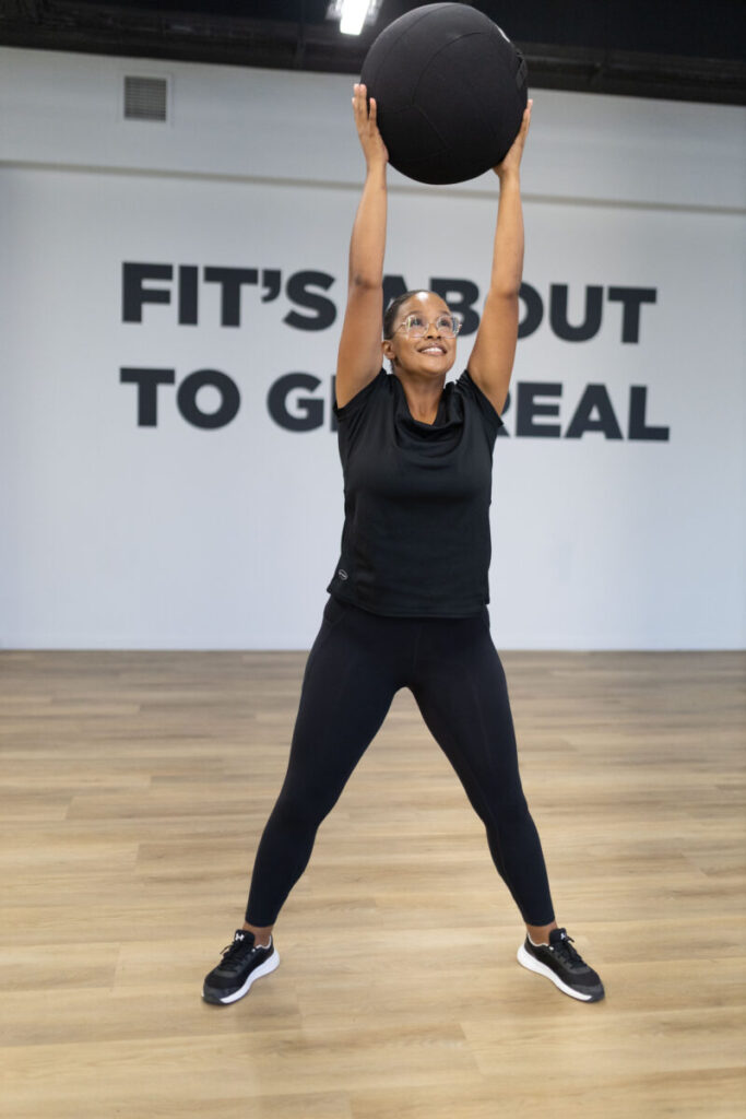 A motivated client performing an overhead slam with a medicine ball at Virgin Active The Sanctuary in Somerset West, delivering a high-intensity cardio workout to boost heart rate and enhance cardiovascular health.
