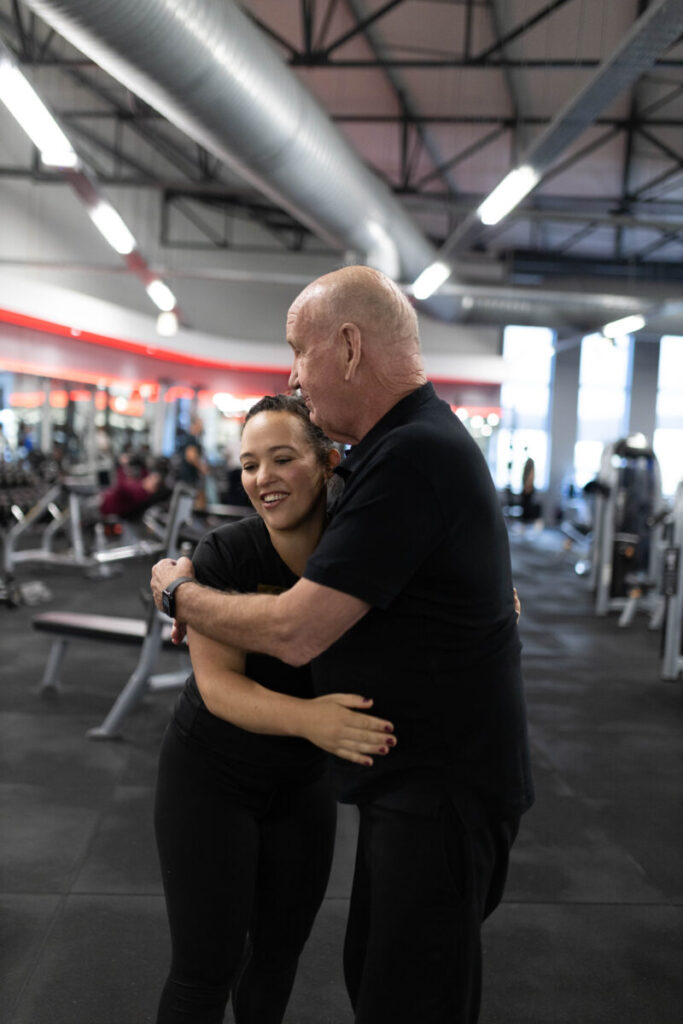 Marcia Swanepoel, a personal trainer at Virgin Active The Sanctuary in Somerset West, sharing a proud embrace with a client after a successful workout, celebrating his dedication and progress in the gym.
