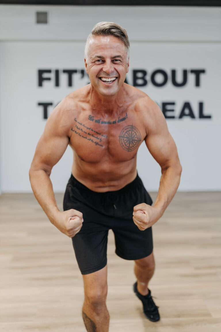 A confident and fit individual flexing triumphantly in a gym at Virgin Active The Sanctuary in Somerset West, embodying the spirit of fitness and vitality at any age.